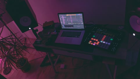 Laptop on a desk with pink and purple lighting - single-use licensing with Soundstripe