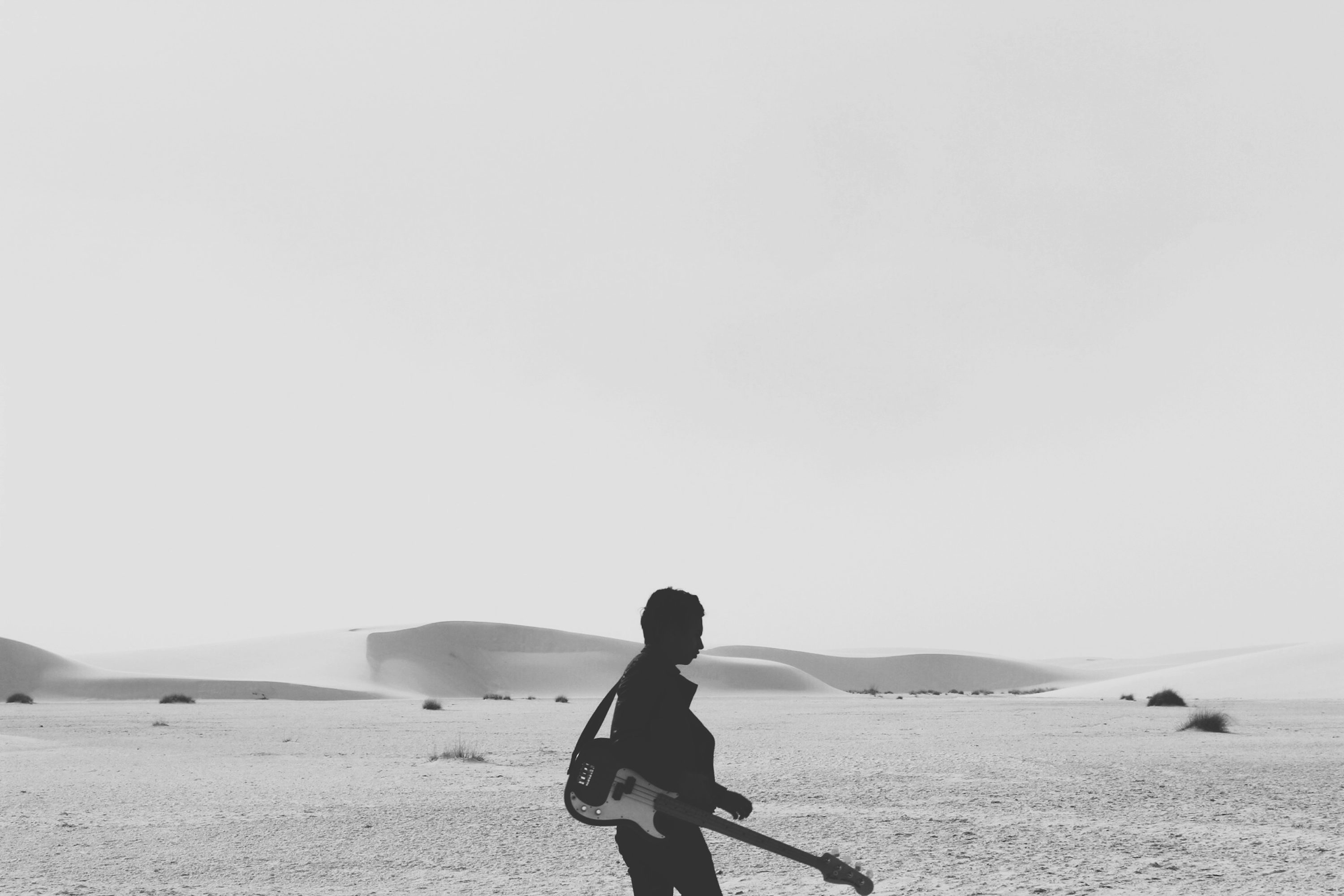 A man walks through a desert holding his a guitar, dreaming up iconic brand sounds