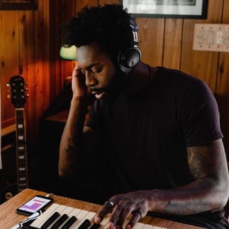 Man recording music on a keyboard, wearing headphones