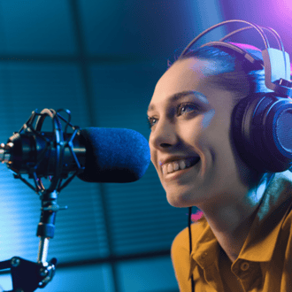 Woman in front of a microphone wearing headphones and recording a podcast