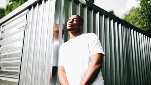 Artist Gee Smiff leans against a building contemplating his many music sync licensing opportunities, and the amazing sync deals music has brought him.