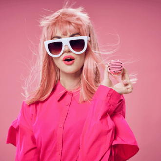 Woman in all pink in front of a pink background holding a cookie