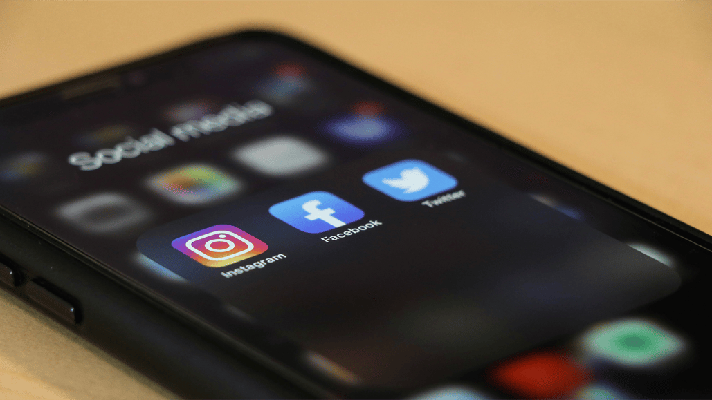 Social media apps are displayed on a black iphone, as a content creator searches for royalty free music for social media videos